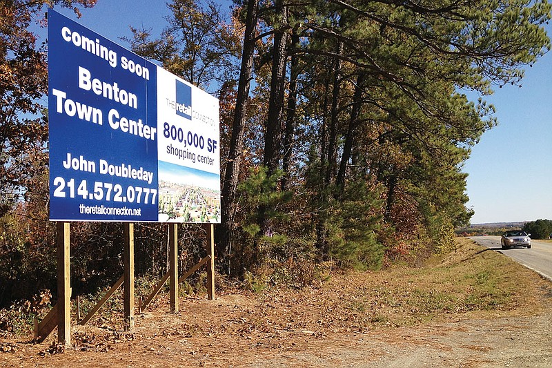 A sign along the Interstate 30 access road west of Exit 114 announces that Benton Town Center, an 800,000-square-foot shopping center, will be coming soon at a site that is mostly woods today.
