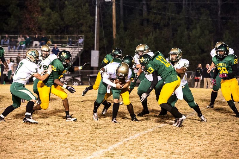 Alma quarterback Gage Jensen (center) is tackled short of the goal line as he tries to score a touchdown in the first half of the Airedales’ 21-20 victory over Mills on Friday. Jensen ran 28 times for 121 yards and 2 touchdowns, and threw for another score, in the victory. Alma (7-4) will play at Camden Fairview, the top-ranked team in Class 5A, in a quarterfinal game next week. Video is available at arkansasonline.com/videos. 