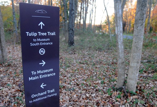 A sign indicates the multiple trail routes visitors can take to an entrance at Crystal Bridges Museum of American Art on Wednesday in Bentonville. The museum grounds have more than 3.5 miles of trail for visitors. 