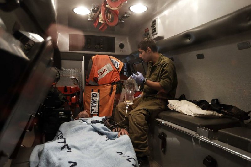 A wounded Israeli soldier is attended to while being evacuated by ambulance Saturday after an explosion targeting an Israeli military vehicle on the Israel-Gaza border. 