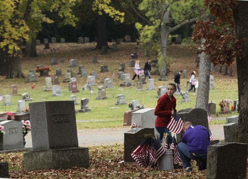 Sarah Green, Spencer Brown and other Mount St. Mary Academy and Catholic High School students put flags on the graves of veterans Saturday at Roselawn Cemetery in Little Rock. 