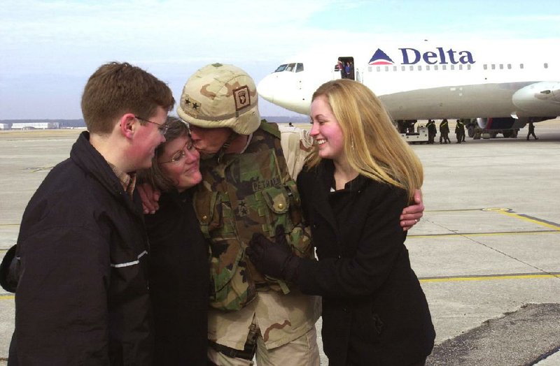 David Petraeus kisses his wife, Holly, as his son Stephen and daughter Anne greet him at Fort Campbell, Ky., after his return from Iraq on Feb. 14, 2004.