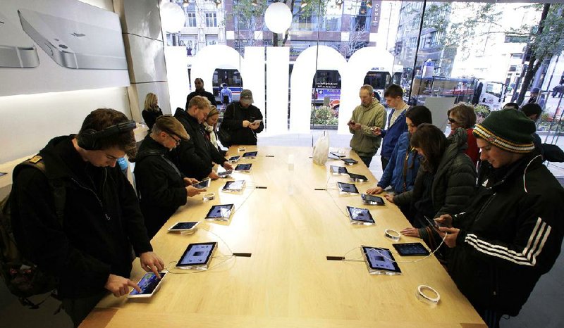 Shoppers check out the new Apple iPad Mini earlier this month at the Apple store on Michigan Avenue in Chicago. 