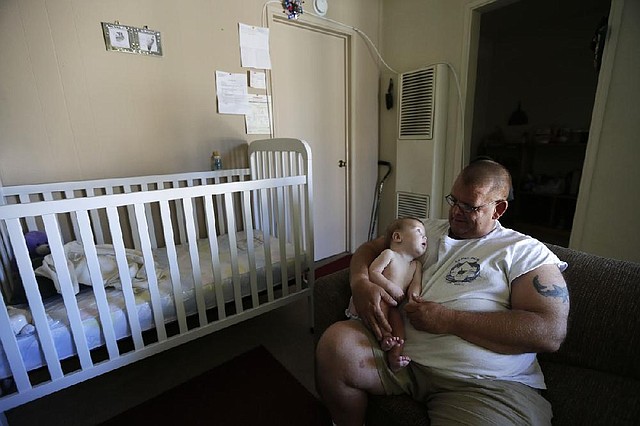 Veteran Arthur Lute holds his 5-month-old son Evan in his apartment in Chula Vista, Calif., last month. 