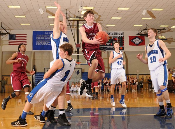 Alex Scharlau, center, Springdale High, finds an open lane to the basket between Rogers High’s Zach Jones, center left, and Cameron Carroll, right, during the Bulldogs’ game Jan. 31 at Rogers High School. 