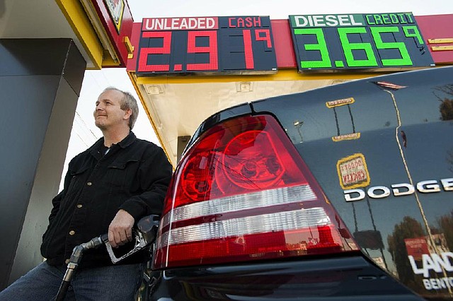 Michael Heavner fills his car with gasoline that cost less than $3 a gallon at the Dodge’s Store on South University Avenue in Little Rock on Monday afternoon. 