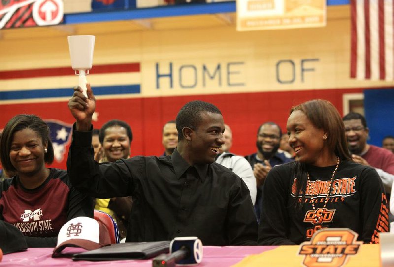 Little Rock Parkview’s I.J. Ready (center) rings a cowbell Wednesday after he and classmate Roshunda Johnson (right) signed to play NCAA Division I basketball on the first day of the early signing period. Ready, seated next to his sister, Natalia, will be attending Mississippi State next season while Johnson is headed to Oklahoma State. 