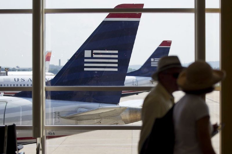Travelers pass US Airways planes at Reagan National Airport in Washington D.C. US Airways is making its case to merge with AMR Corp.’s bankrupt American Airlines in meetings this week with American Airlines and its creditors. 