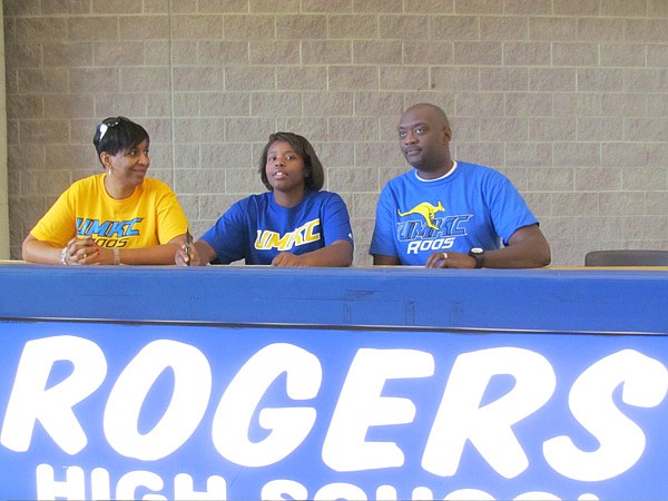 Taylor Strickland, a Rogers High senior, signs to play basketball at Missouri-Kansas City while her parents, Edwin and Shun Strickland, look on. 
