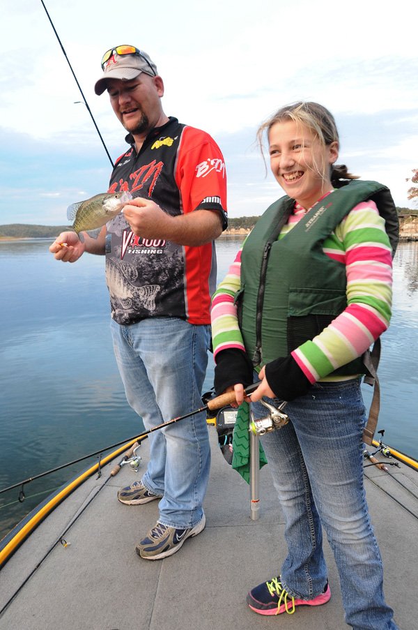 Katelyn Piper and her dad, fishing guide Jason Piper of Rogers, work jigs around timber for crappie Friday in the Horseshoe Bend area of Beaver Lake. Fishing has been good this fall around timber and docks, the Piper team said. 