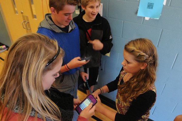 Mackenzie Harrell, from left, Collin Adams, Jared Dickey and Maddi McKinney, Kirksey Middle School students, check phones for instructions Wednesday after scanning the code at upper right during a technology adventure race. The activity combines physical education with learning academic subjects such as math, science and music. 