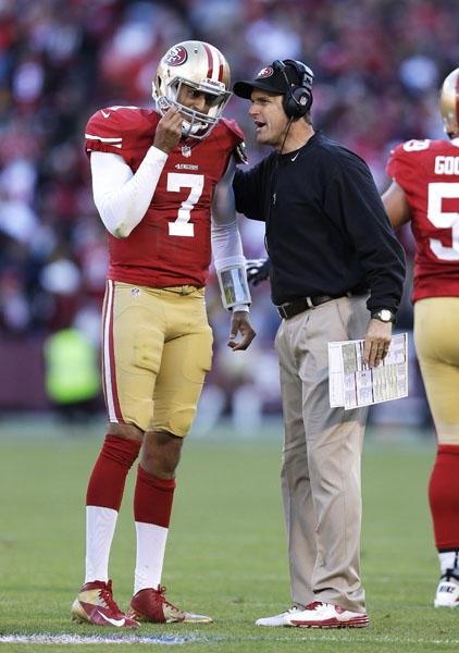 San Francisco 49ers Coach Jim Harbaugh (right) speaks with quarterback Colin Kaepernick during Sunday’s game. Harbaugh was hospitalized Thursday for a “minor procedure.” 