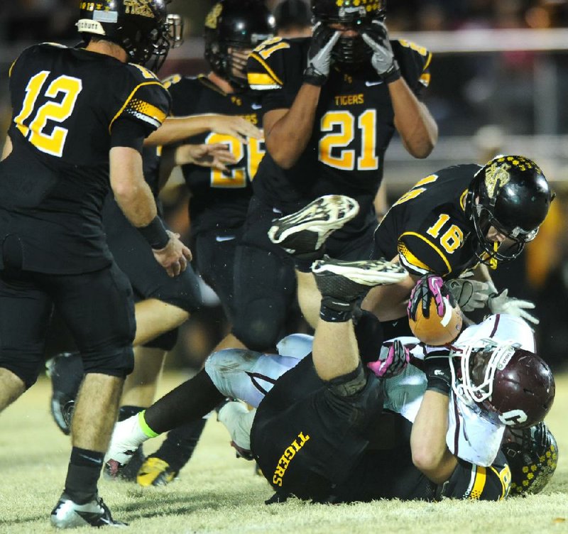 Prairie Grove defenders Jacob Kahl (bottom) and Dalton Faulk (16) bring down Crossett running back Dominic Williams during last Friday’s game in Prairie Grove. The Tigers’ defense has allowed only 2.7 points per game this season. 