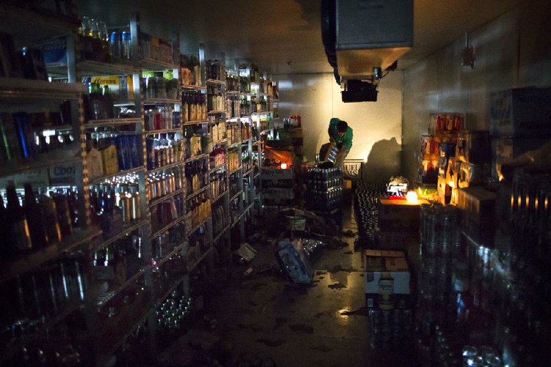 A worker cleans out a walk-in refrigerator at the West Side Wine & Liquor store in Hoboken, N.J., last week. The Labor Department said superstorm Sandy drove the number of people seeking unemployment benefits up last week. 