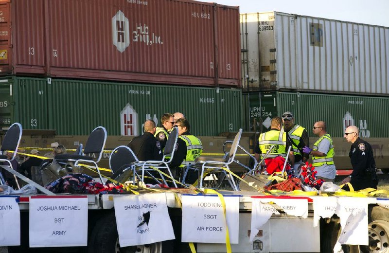 Police, fire and sheriff’s personnel respond to an accident in which a flatbed trailer carrying wounded veterans in a parade was struck by a train at a crossing Thursday in Midland, Texas.