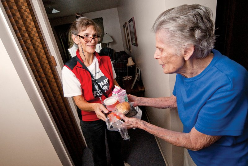 Aileen Barnett, right, receives a delivery from Marion Scott, who distributes Meals on Wheels as part of her volunteer activities in Maumelle. That and other endeavors by Scott and people in the city led to Maumelle being named a 2012 Volunteer Community of the Year.