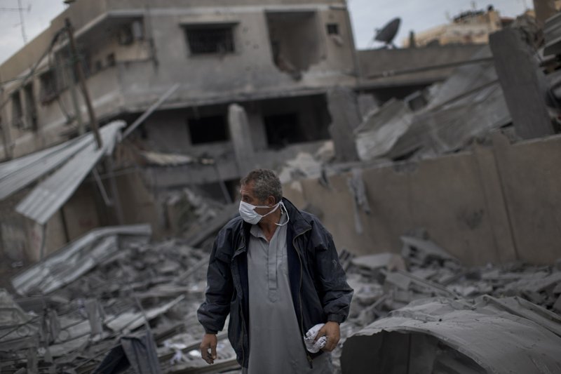 A Palestinian man walks among debris after an Israeli airstrike at Hamas Prime Minister Ismail Haniyeh's office, right, in Gaza City, Saturday, Nov. 17, 2012. Israel bombarded the Hamas-ruled Gaza Strip with more than 180 airstrikes early Saturday, widening a blistering assault on militant operations to target government and police compounds and a vast network of smuggling tunnels.