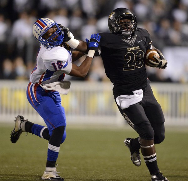 Tearris Wallace, right, a Bentonville running back, stiff-arms West Memphis defensive back Calman Clark on a 16-yard carry Friday during the first quarter at Tiger Stadium in Bentonville. 