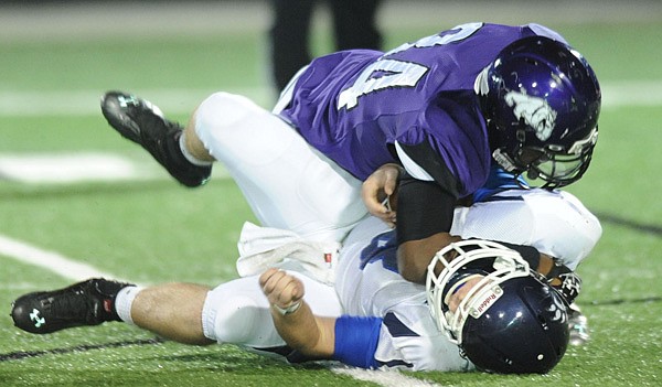 Taryll Henry, top, a Fayetteville senior defensive end, sacks Conway senior quarterback Cody Rhoades on Friday during the first half of play at Harmon Stadium. 