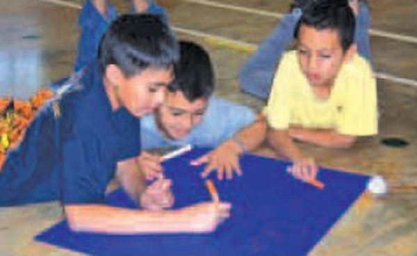 Giovanni Train, from left, Nicholas Sanchez and Jose Leon, all Monitor Elementary School students, work Thursday on a sign they will use to root each other on at today’s Big Event in Springdale. 