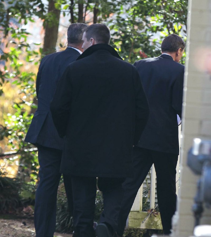 Former CIA Director David Petraeus (right) enters his home Friday in Arlington, Va., accompanied by security guards after testifying on Capitol Hill before the Senate and House intelligence committees. 