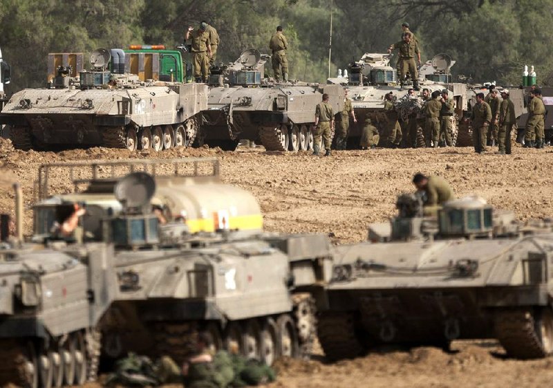 Israeli soldiers work on their tanks Friday in a staging ground near the Gaza Strip border in southern Israel. Friday marked the third consecutive day Israeli forces exchanged fire with Hamas. 