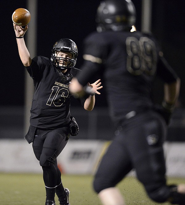 Reese Dollins, left, Bentonville’s quarterback, passes the ball to tight end Chase Morse on Friday during the Tigers’ Class 7A playoff game at Tiger Stadium in Bentonville. 