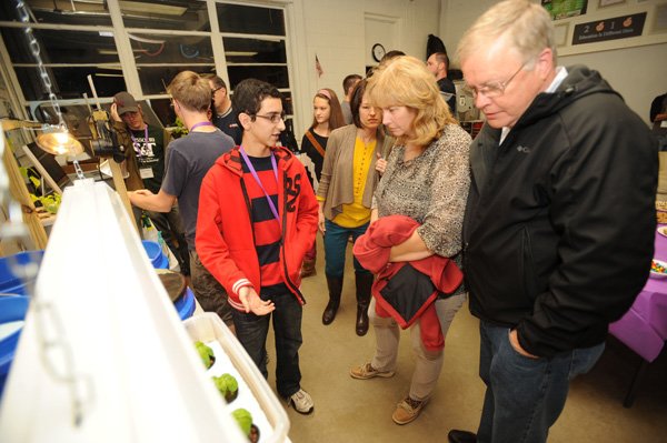 Daniel Carmona, a Fayetteville High School junior, left, explains a bucket garden system Nov. 8 to visitors Sherry and Jim Kribs during an Environmental and Spatial Technology Lab Night Out event at the Fayetteville High School’s West Campus in Fayetteville. 