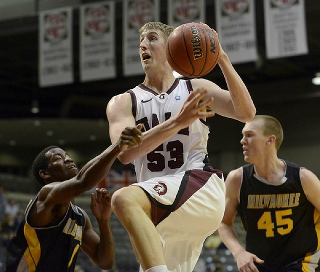 UALR forward Will Neighbour (53) leaps past Wisconsin-Milwaukee’s Jordan Aaron (left) and Christian Wolf during Monday’s game at the Jack Stephens Center in Little Rock. Neighbour finished with 17 points. 