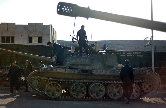 Syrian rebel fighters check a tank they captured Monday after storming a military base in Aleppo, Syria’s largest city. 