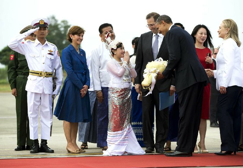 President Barack Obama is presented with flowers as he and Secretary of State Hillary Rodham Clinton (right) arrive today at Rangoon International Airport in Rangoon, Burma. 