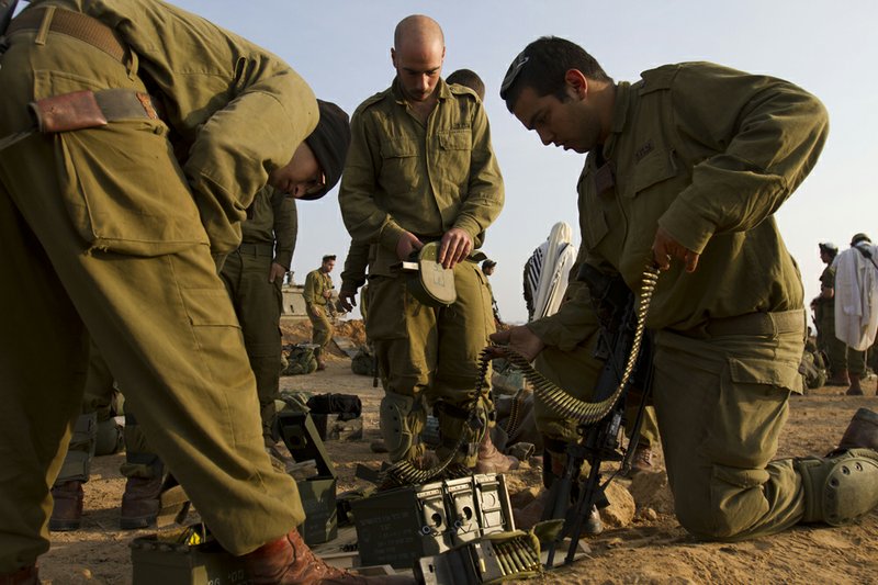 Israeli soldiers prepare their ammunition Monday in a staging area near the Israel-Gaza Strip border in southern Israel. The Palestinian civilian death toll mounts as Israel pursues Gaza Strip militants who have been firing rockets into Israel. 