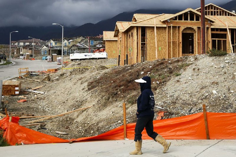 A woman walks past houses under construction in Rancho Cucamonga, Calif., on Sunday. The Commerce Department said housing starts in October rose to a four-year high. 