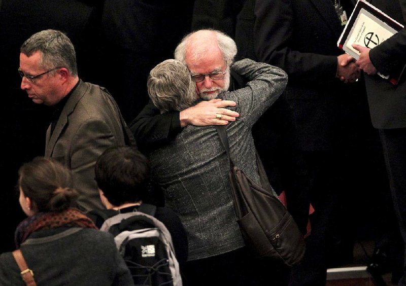 Outgoing Archbishop of Canterbury Rowan Williams embraces a woman colleague after draft legislation introducing the first women bishops in the Church of England failed to receive final approval from the church’s General Synod on Tuesday at Church House in central London. 