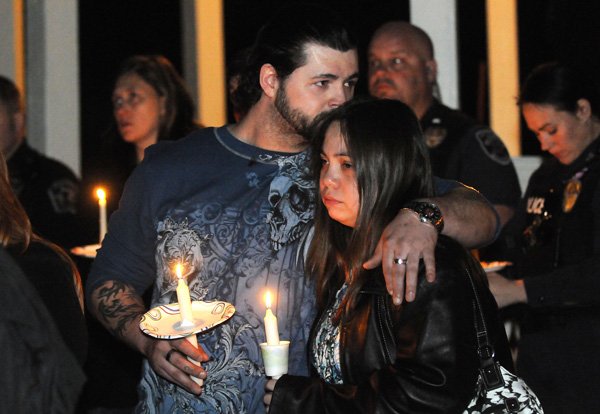 Mike Bridgeman, left, uncle of Jersey Bridgeman, kisses Laurie Caancan on the top of the head Tuesday during a candlelight vigil at the Children’s Advocacy Center of Benton County’s Memory Garden in Little Flock. 