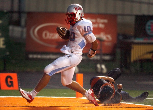 Issac Jackson, Fort Smith Southside’s junior quarterback, runs into the end zone for a touchdown past the tackle attempt from senior defensive back Utah Julius on Aug. 31 at David Gates Stadium in Rogers. 