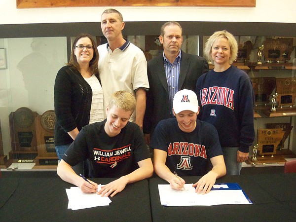 Lane Brand, seated left, and Gage Crosby, Bentonville swimmers, sign their national letters of intent with William Jewell College and Arizona, respectively, during Tuesday’s ceremony at the high school. Joining them for the occasion are their parents, from left, Leslie and Rodney Bland and Clayton and Monica Crosby. 