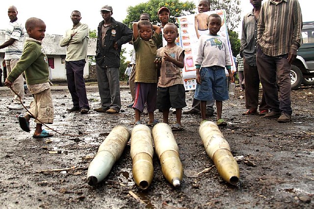 People gather around tank shells left behind by retreating government troops Wednesday as they fled an assault by M23 rebels in eastern Congo. 