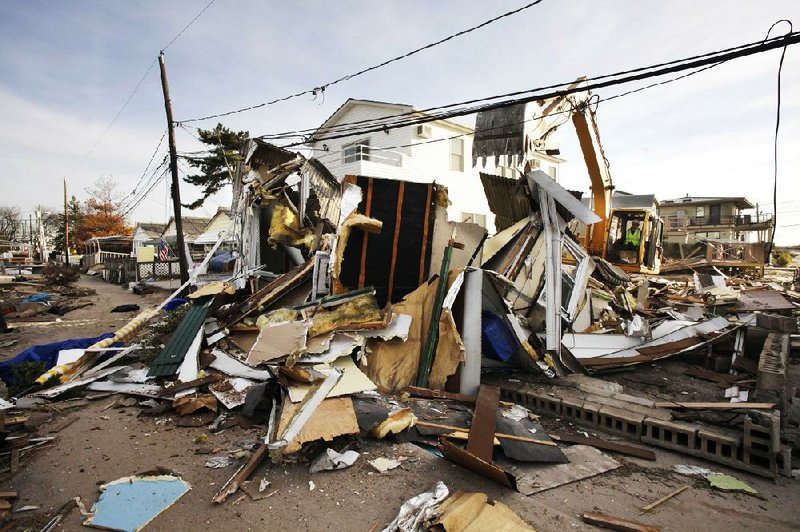 A backhoe levels a storm-damaged home Tuesday in the Breezy Point section of the Queens borough of New York. 