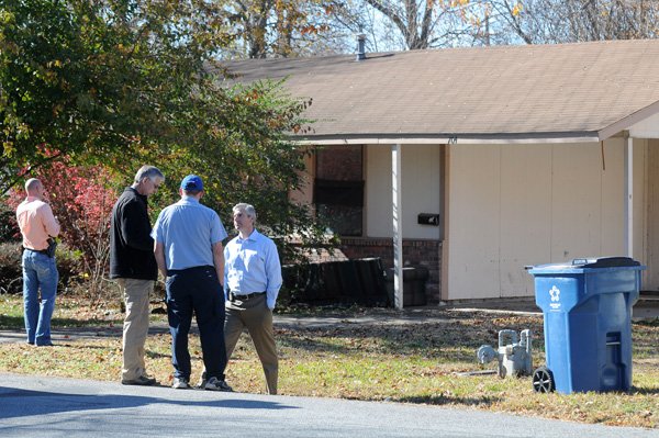 Wes Bryant, left, cart coordinator with the Benton County Child Abduction Response Team, looks Wednesday at the house Jersey Bridgeman was found in while FBI agents speak with a neighbor at 704 S.E. A St. in Bentonville. Jersey’s body was found Tuesday morning after she was reported missing. Her death is being investigated as a homicide. 