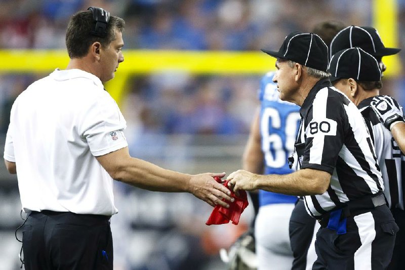 Field judge Greg Gautreaux (right) hands the red challenge flag back to Detroit Coach Jim Schwartz during the Lions’ 34-31 overtime loss to the Houston Texans on Thursday in Detroit. Schwartz threw a challenge flag when Houston’s Justin Forsett scored on an 81-yard run in the third quarter. Replays showed Forsett was down near midfield, but Schwartz negated the automatic review by challenging the play and was called for unsportsmanlike conduct. 