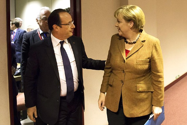 French President Francois Hollande greets German Chancellor Angela Merkel during a European Union summit session Thursday in Brussels. 