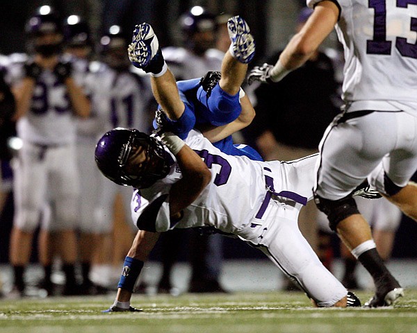 Heath McCracken, a Fayetteville strong safety, upends Rogers High senior running back Zachary Raphael on Oct. 12 at Mountie Stadium in Rogers. After two seasons as a backup quarterback for the Bulldogs, McCracken has been able to focus on defense during his senior year.