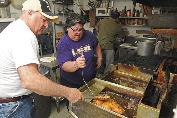 Maudie Schmitt, center, owner of Cafe Rue Orleans in Fayetteville, turns a turkey in a fryer Thursday with the help of her brother Thomas Schmitt. Maudie is cooking a large Thanksgiving meal for 70 friends and family, some of whom have come to Fayetteville for football game between the University of Arkansas and Louisiana State University. 
