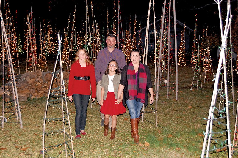 The Lee family of Malvern, front, from the left, Morgan, Megan and mother Tonya; and father Thomas, rear, walk through the bamboo Christmas trees built by the Burns brothers in Malvern. Malvern and Hot Spring County residents, along with visitors from around the country, visit the brothers’ family home to enjoy the holiday lights.