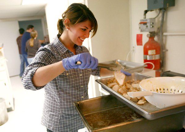 Ashley Evilsizor moves pieces of turkey to a tray at Charity Baptist Church on Thursday in Rogers. For the
second year, Executive Chef John Chervenyak and his wife, Nicole, organized the event to prepare and serve complimentary Thanksgiving meals.