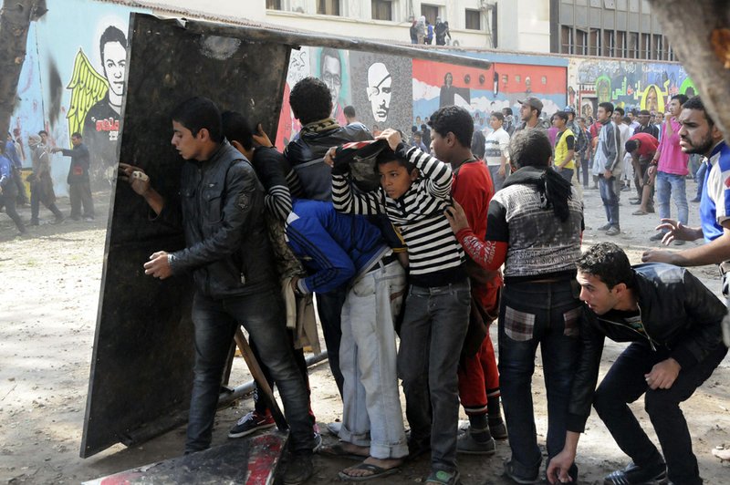 Egyptian protesters opposed to President Mohammed Morsi take cover during clashes with Morsi supporters near Tahrir Square in Cairo on Friday, Nov. 23, 2012. 