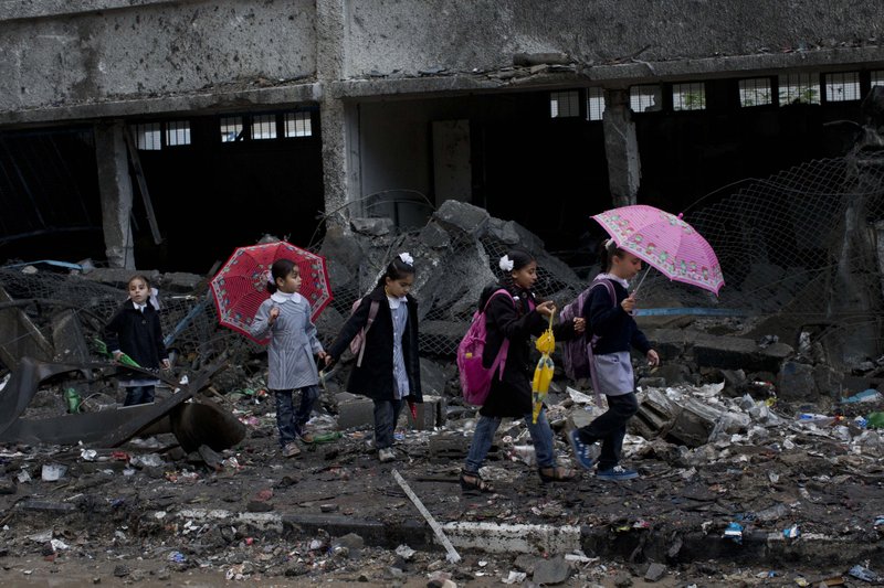 Palestinian schoolchildren walk in debris by a damaged school in Gaza City, Saturday, Nov. 24, 2012. Schools in Gaza opened Saturday for the first time since the truce, which calls for an end to Gaza rocket fire on Israel and Israeli airstrikes on Gaza, came after eight days of cross-border fighting, the bloodiest between Israel and Hamas in four years. The school was damaged when Israeli forces struck on a nearby building.