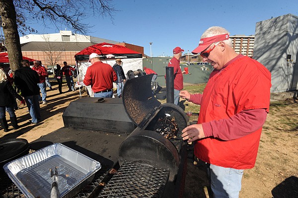 Mike Moffett of Fayetteville checks on a piece of meat he was smoking Friday while tailgating with friends before the University of Arkansas football game with Louisiana State in front of Bud Walton Arena in Fayetteville. 