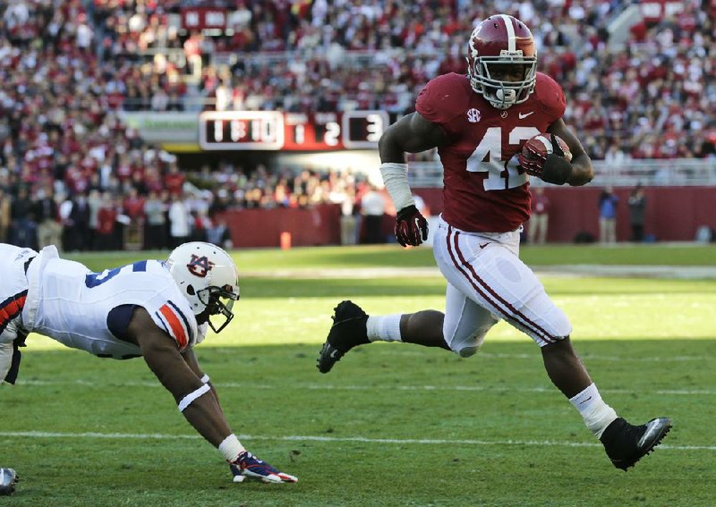 Alabama running back Eddie Lacy (42) scores a touchdown ahead of Auburn defensive end Dee Ford (left) during the first half of the No. 2 Crimson Tide’s 49-0 victory Saturday in Tuscaloosa, Ala. 